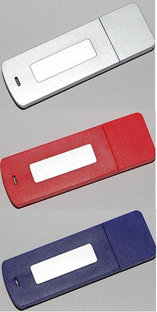 Trzy pendrive'y w kolorach srebrnym, czerwonym i granatowym z białymi polami na nadruk reklamowy, ułożone jeden pod drugim.